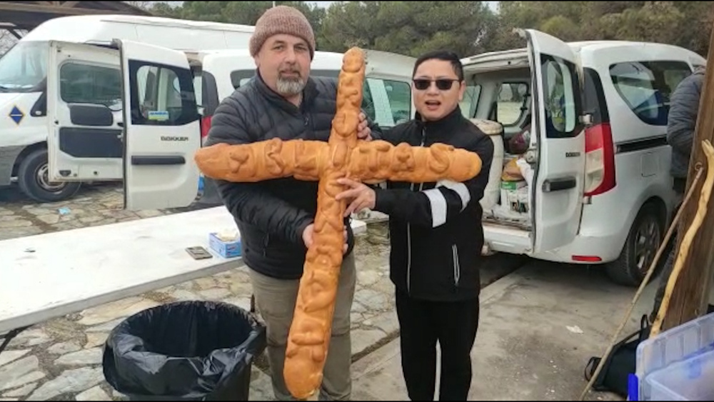 Alfonso Baigorri, panadero de Ablitas, entre un pan con forma de cruz al párroco de su localidad, Huynh Nguyen