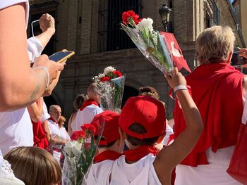 Los niños ofrecen flores rojas y blancas a San Fermín